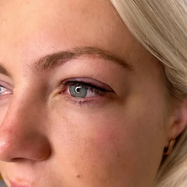 Subtle eyeliner tattoo on blonde client — natural definition for blue eyes