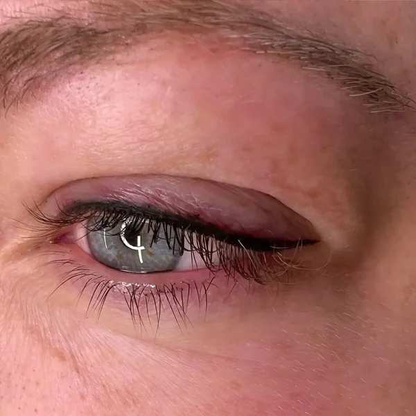 Winged eyeliner tattoo on mature skin — defined cat-eye flick
